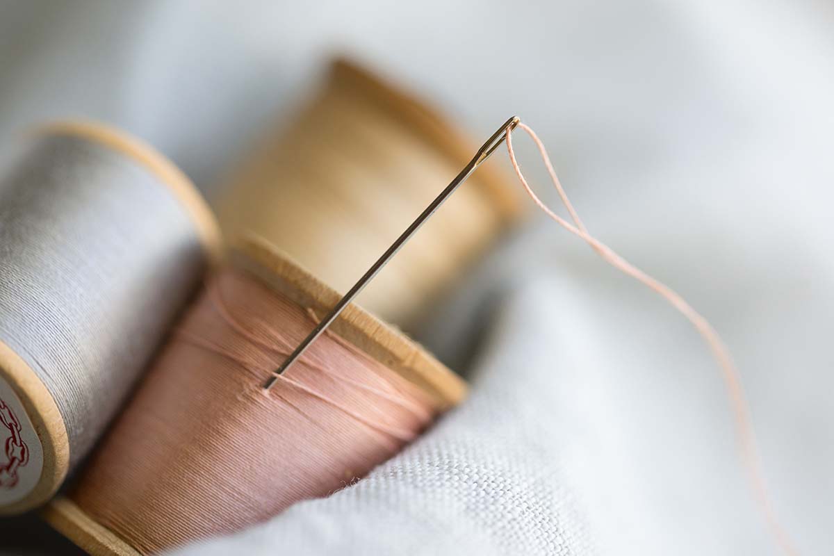 Close up of needle in thread spool with two others