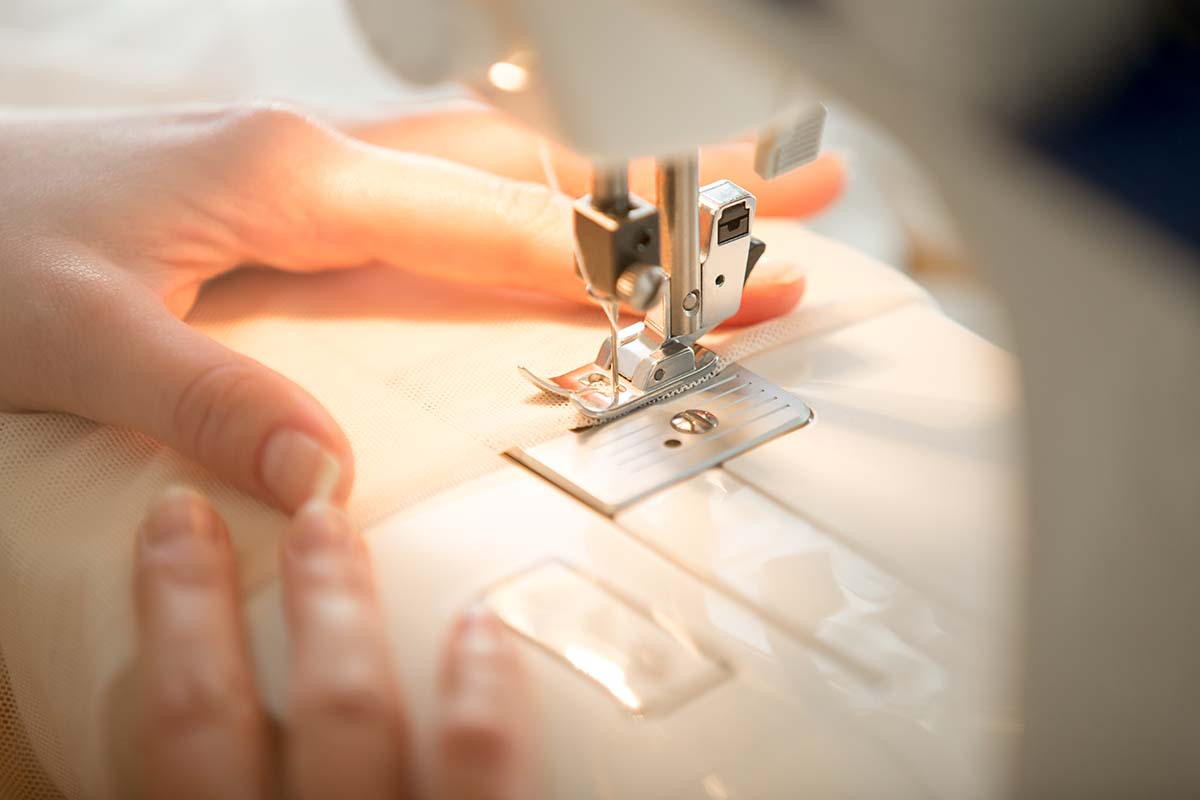 Close up on a hand and sewing machine.